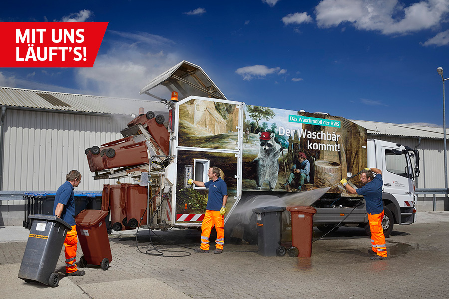 Ein Mitarbeiter der HWS reinigt Restmüll- sowie Biotonnen. Im Hintergrund befindet sich das Waschmobil, welches zur Reinigung von Müllbehältern dient.