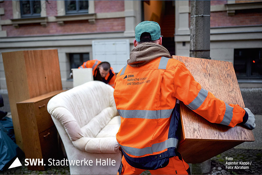 Mitarbeiter in Orange hebt Holzschrank an